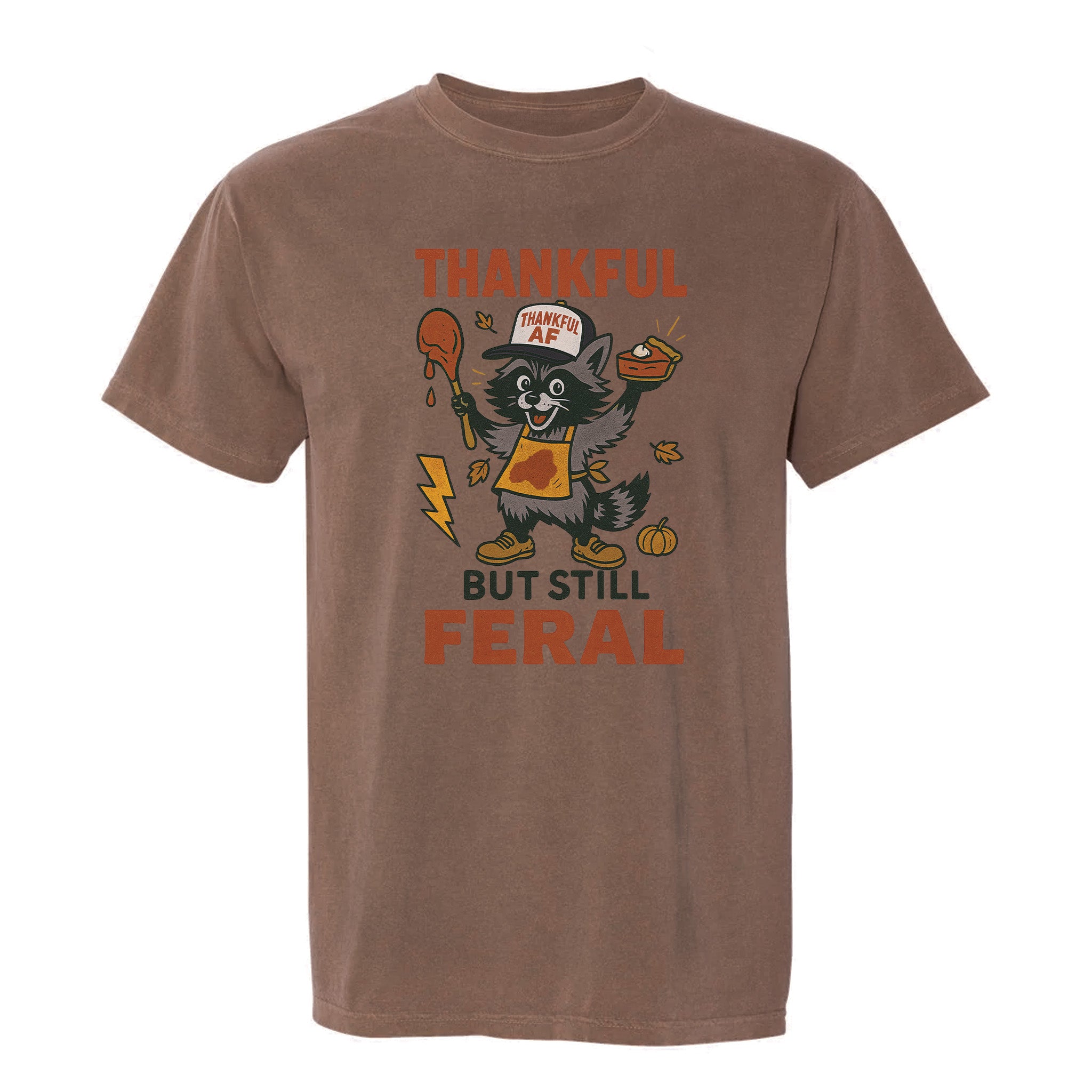 Brown Thanksgiving graphic t-shirt with text 'Thankful but still feral' on a white background.