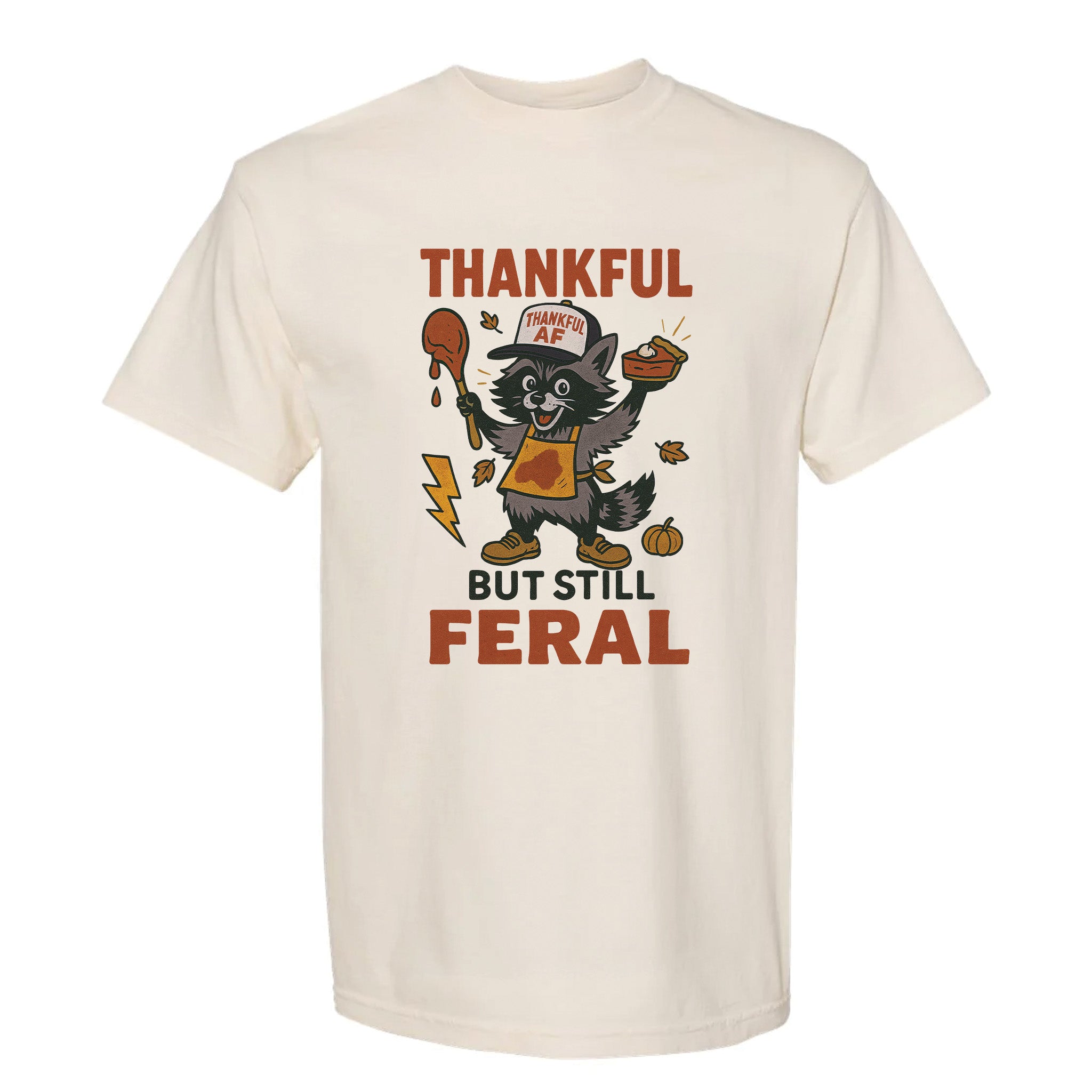 Beige Thanksgiving graphic t-shirt with text 'Thankful but still feral' on a white background.